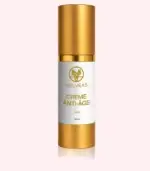 Flacon doré Velvéas Crème Anti-Âge Face 50 ml avec bouchon et base dorés sur fond rose pâle