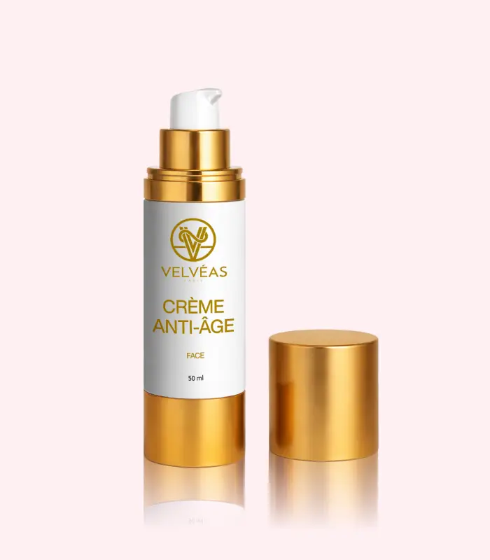 Flacon ouvert Velvéas Crème Anti-Âge Face 50 ml avec pompe doseuse et capuchon doré posé à côté sur fond rose pâle